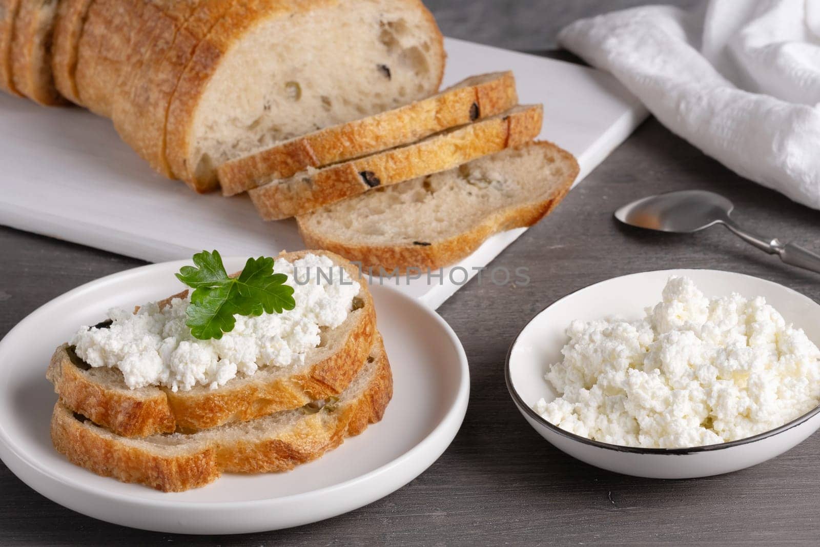 Home made bread on a wooden cutting board with curd cheese.