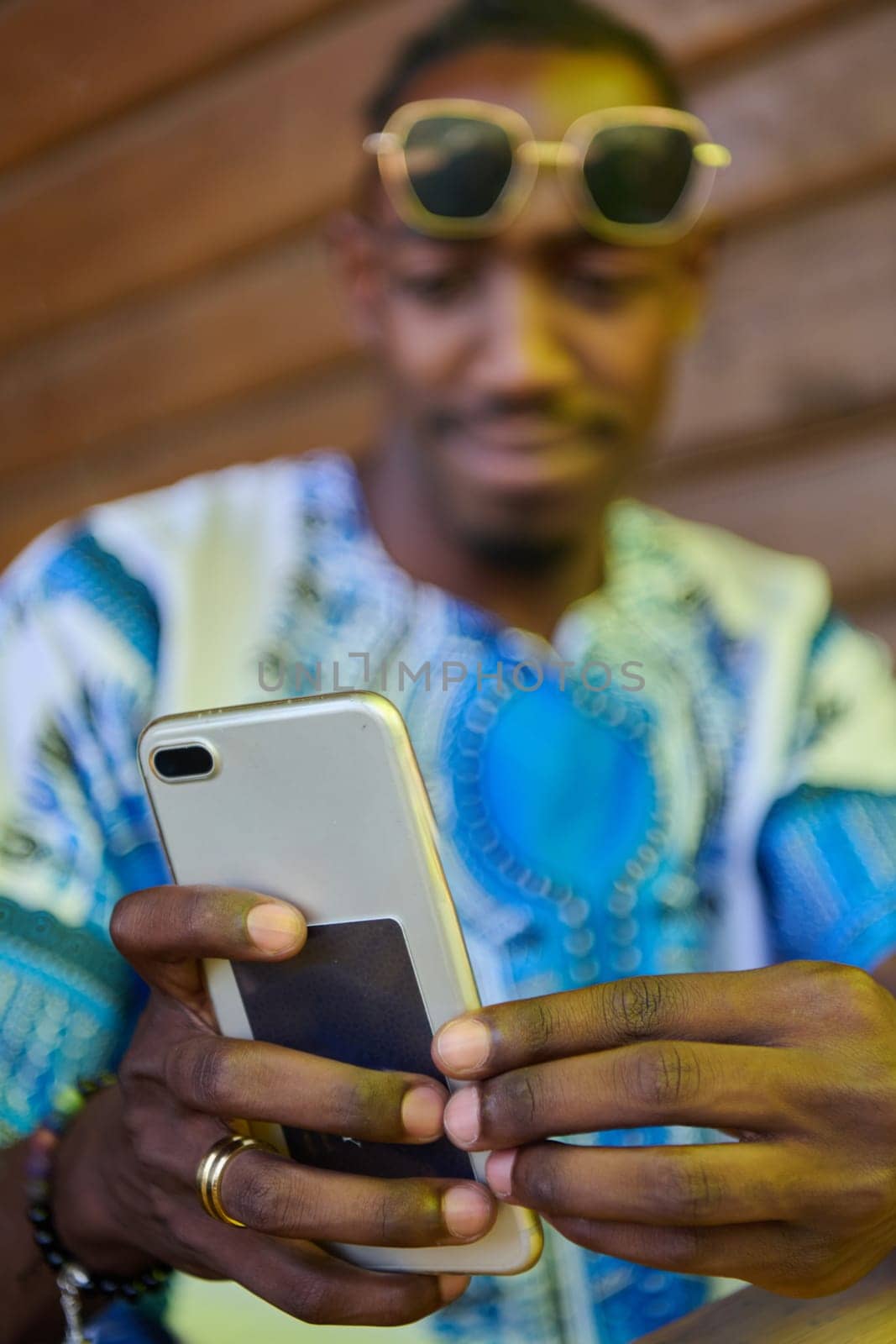 African American teenager adorned in traditional Sudanese clothing, seamlessly navigating the digital world with a smartphone in hand.