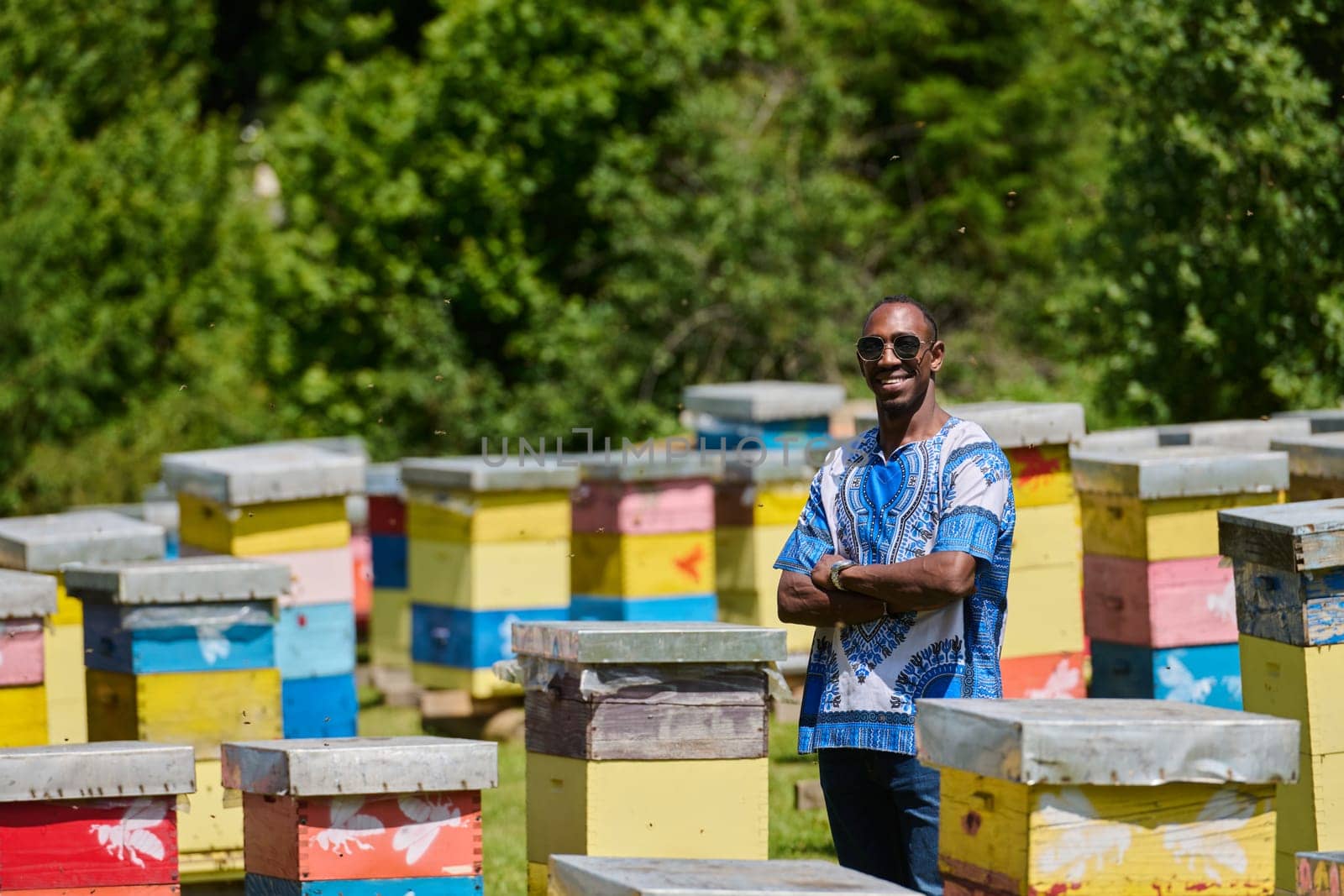 African American teenager clad in traditional Sudanese attire explores small beekeeping businesses amidst the beauty of nature