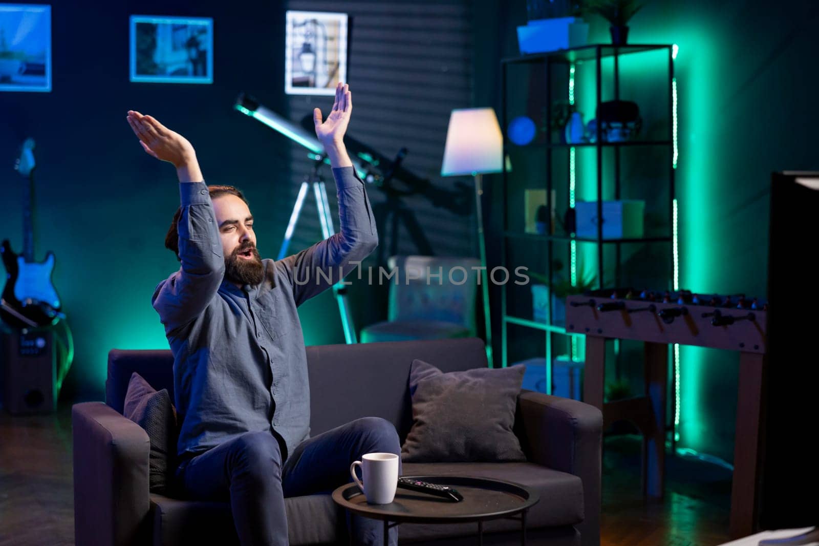 Jolly man clapping hands after favorite team wins while watching live sports event broadcasted on TV. Happy supporter applauding own club, enjoying football competition victory