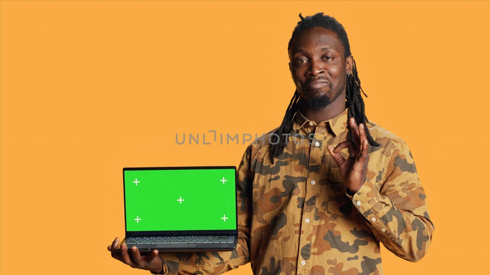 Person having laptop with greenscreen display on camera, posing with blank chromakey layout on wireless pc. Young man presenting computer with isolated copyspace screen in studio.