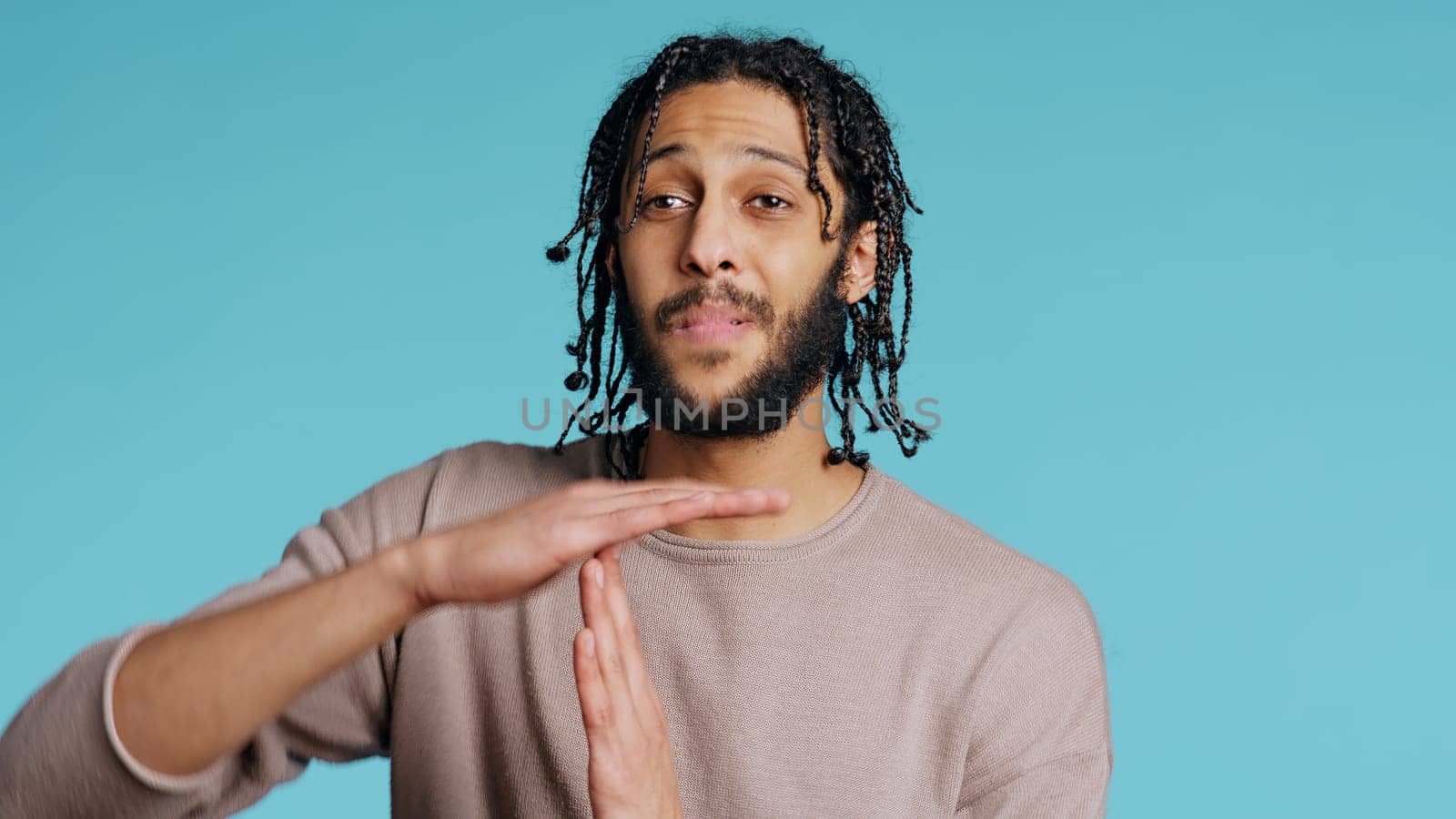 Assertive man asking for timeout, doing hand gestures, studio background by DCStudio