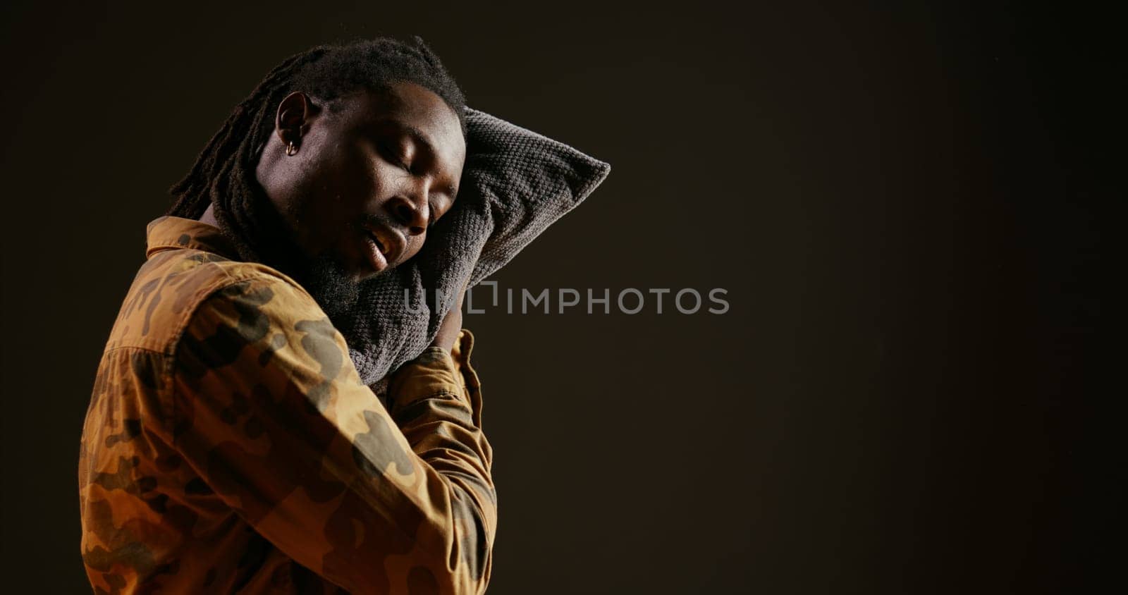 Sleepy person napping with his pillow while he is standing, falling asleep on camera because of burnout and fatigue. Tired african american guy feeling exhausted and overworked, insomnia concept.