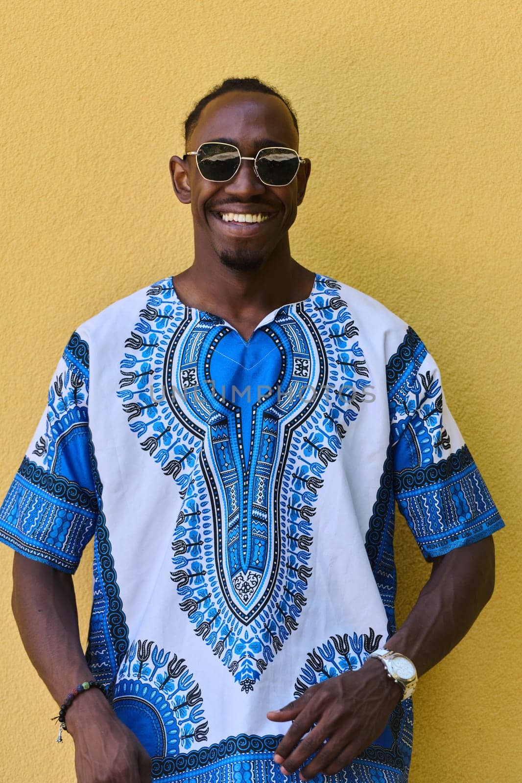 A vibrant portrait of an African American teenager proudly wearing traditional Sudanese clothing against a striking yellow background.