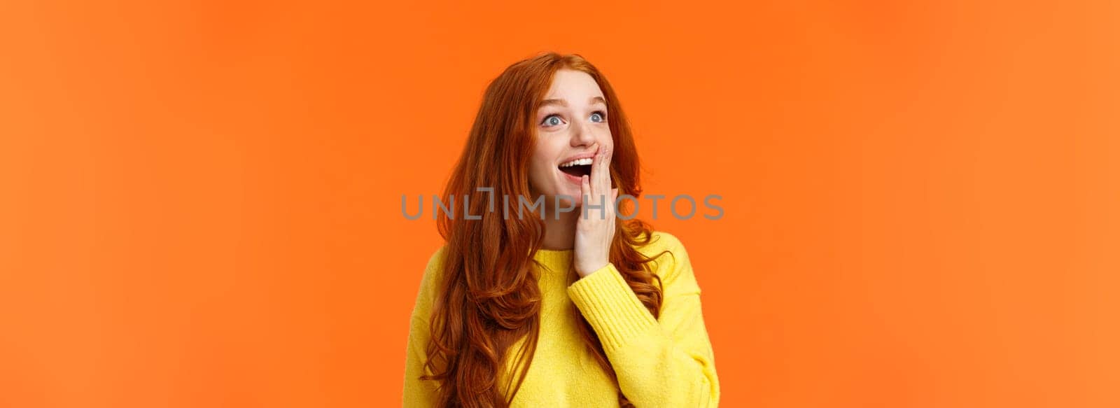 Fascinated and amiring cute redhead woman looking impressed and excited at upper left corner, smiling see breathtaking view, cover opened mouth palm thrilled, losing speech happy, orange background by Benzoix