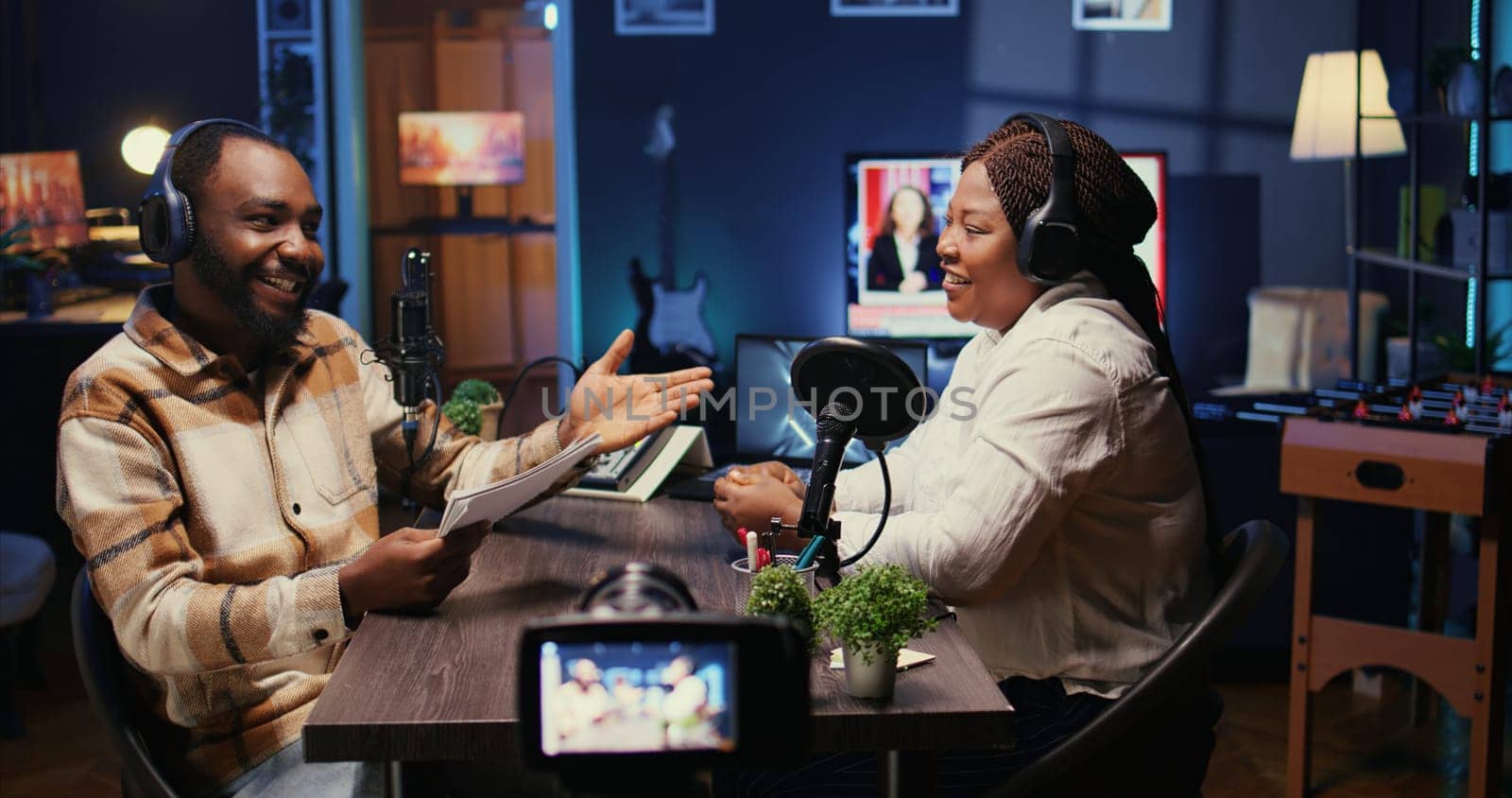 Cohosts streaming podcast using vlogging camera during live debate on vlog channel, handheld camera shot. Man and woman meeting in studio to film show with professional equipment