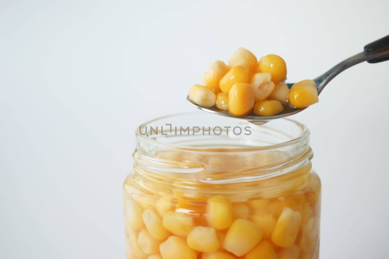 spoon pick Sweet corns from a container .