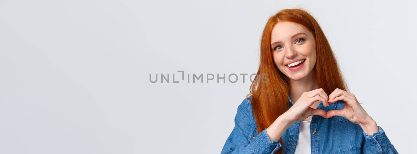 Happy valentines day, love. Cute and tender romantic redhead girlfriend showing heart sign, confess in sympathy, express passion or like, admire amazing artwork, appreciate, stand white background by Benzoix