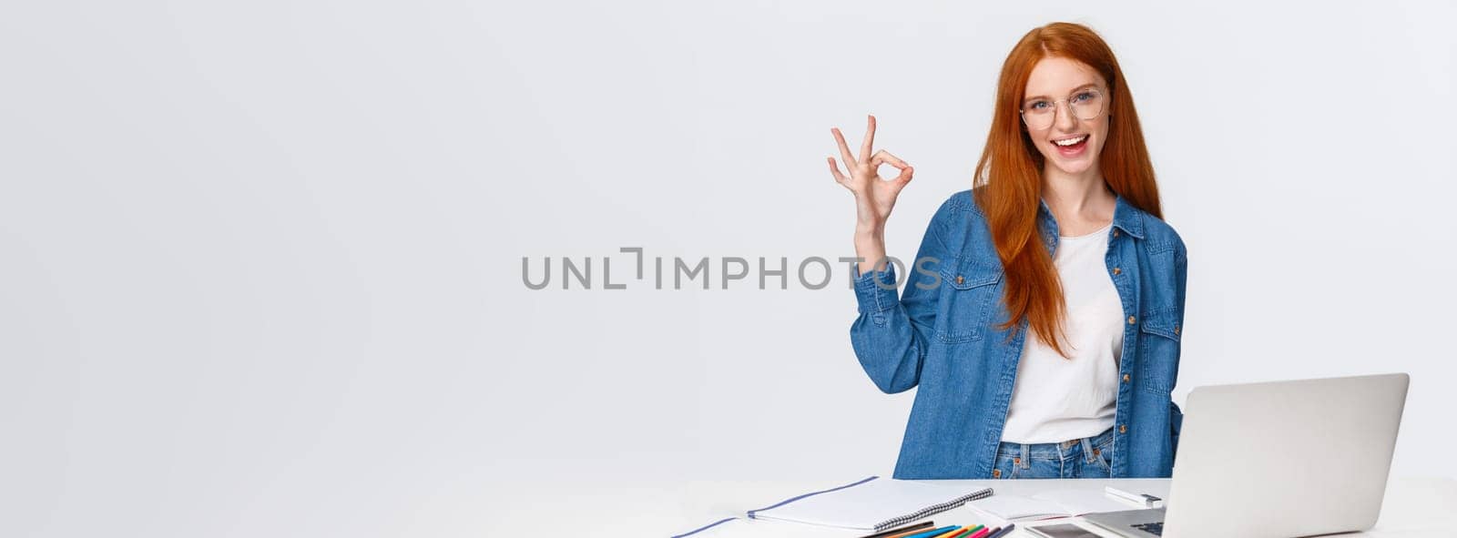 No problem, everything excellent. Confident creative redhead woman have plan, prepare design project, working with team on drawing, standing near table with laptop, colored pencils, show ok by Benzoix