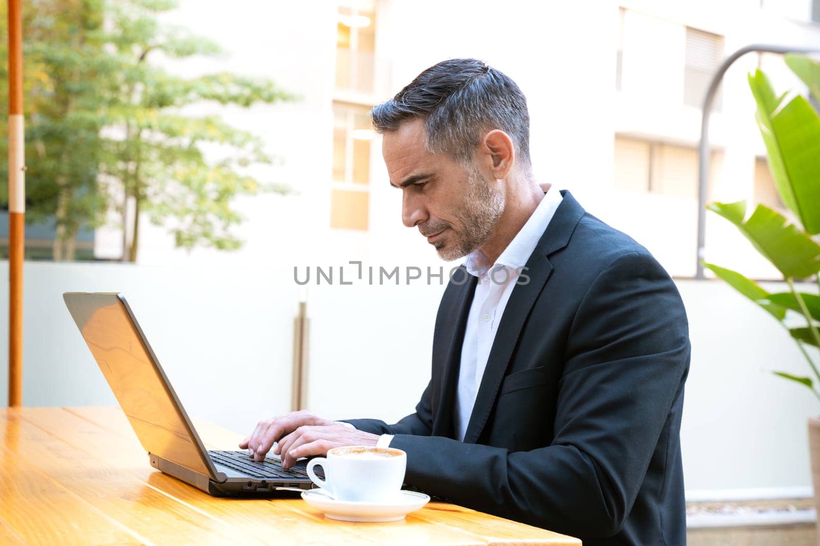 Business on the move: Businessman working on his laptop on the street. Man Hands Type On His Laptop Outdoors