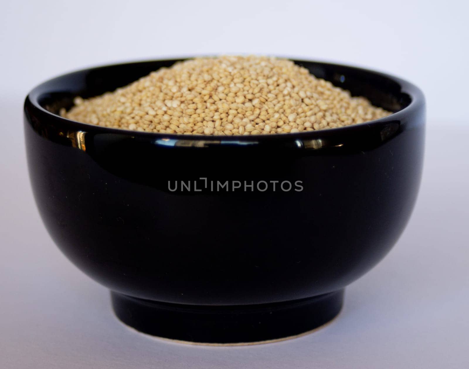 Quinoa grains in black bowl. side view picture in white background. by VeroDibe