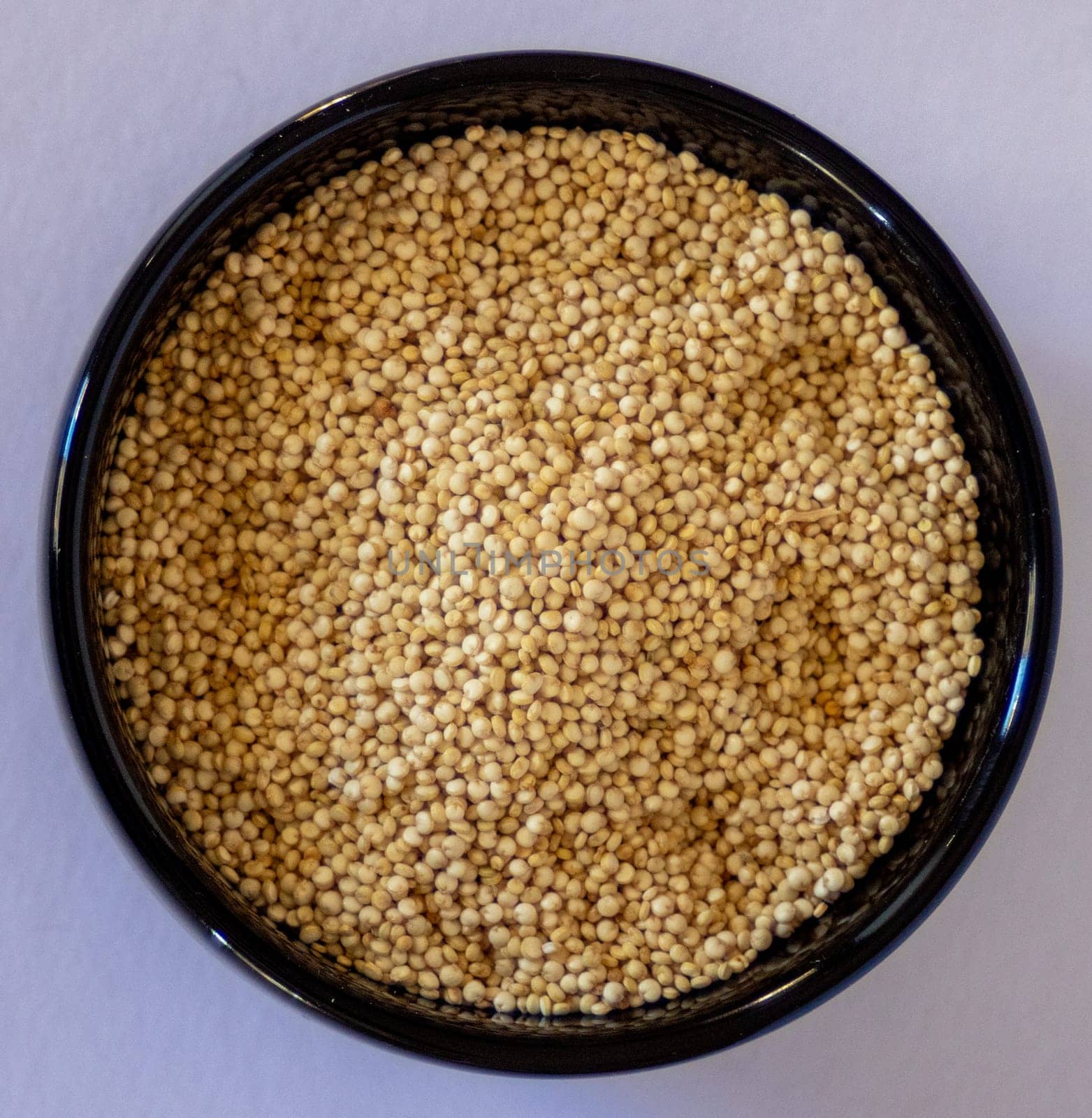 Quinoa seeds in black bowl in white background. Cenital photo.Healthy food by VeroDibe