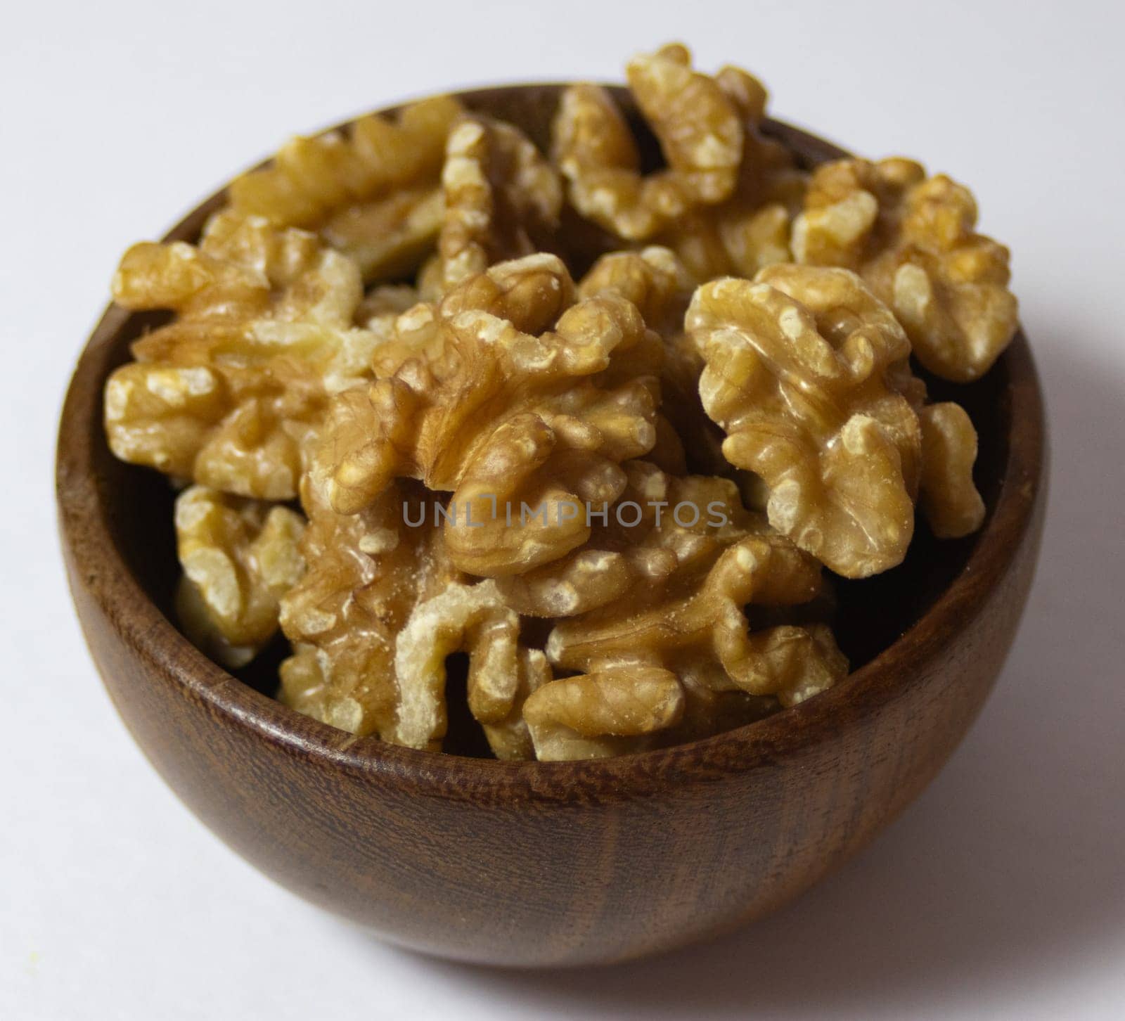 Roasted walnuts in bowl in wooden bowl. 45 degree picture. Close up. Source of healthy fat acids. Vegan food