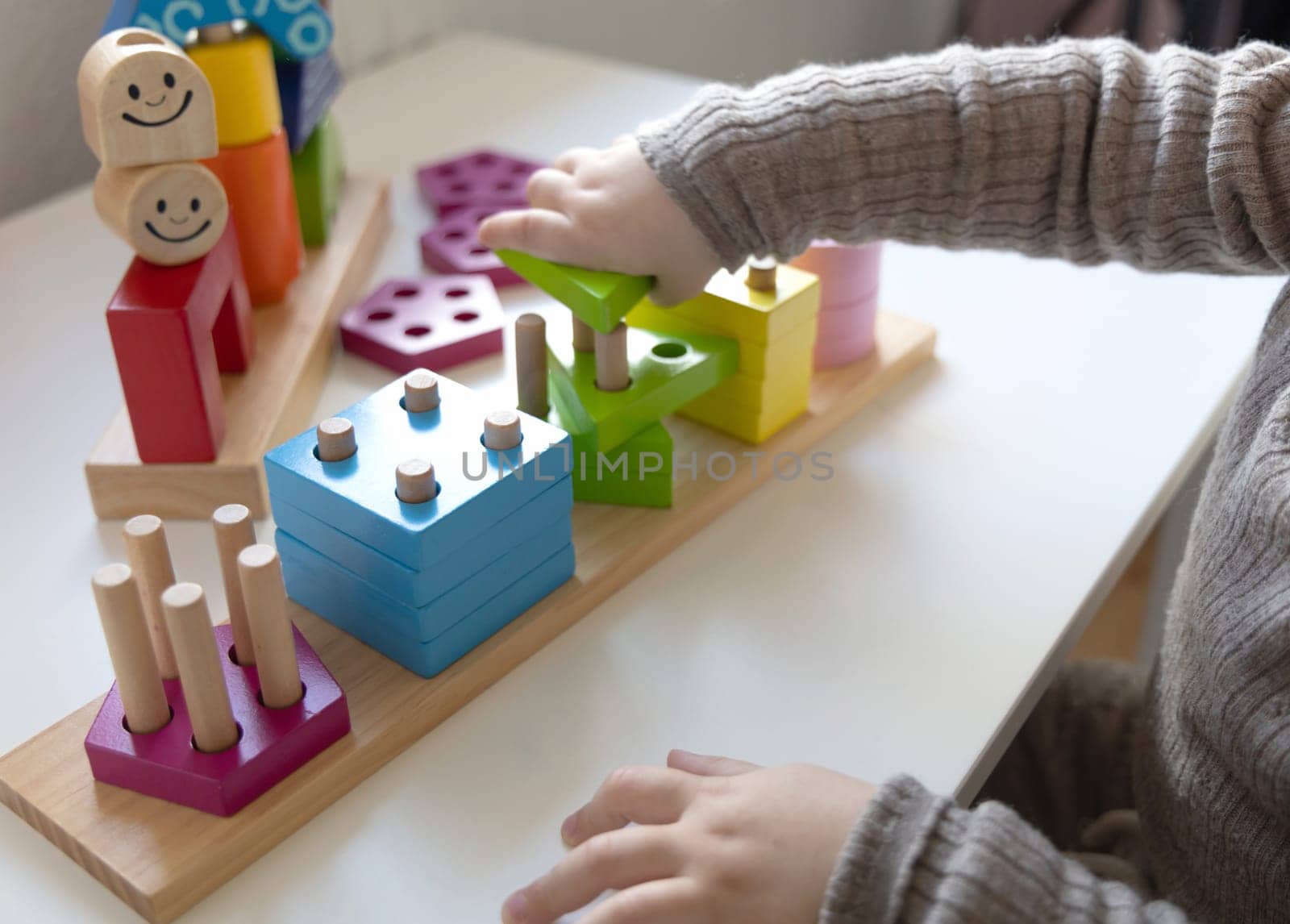 Child playing a fun-filled game of logic with colourful wooden blocks. Game of logic. Educational games for children and earlier development.