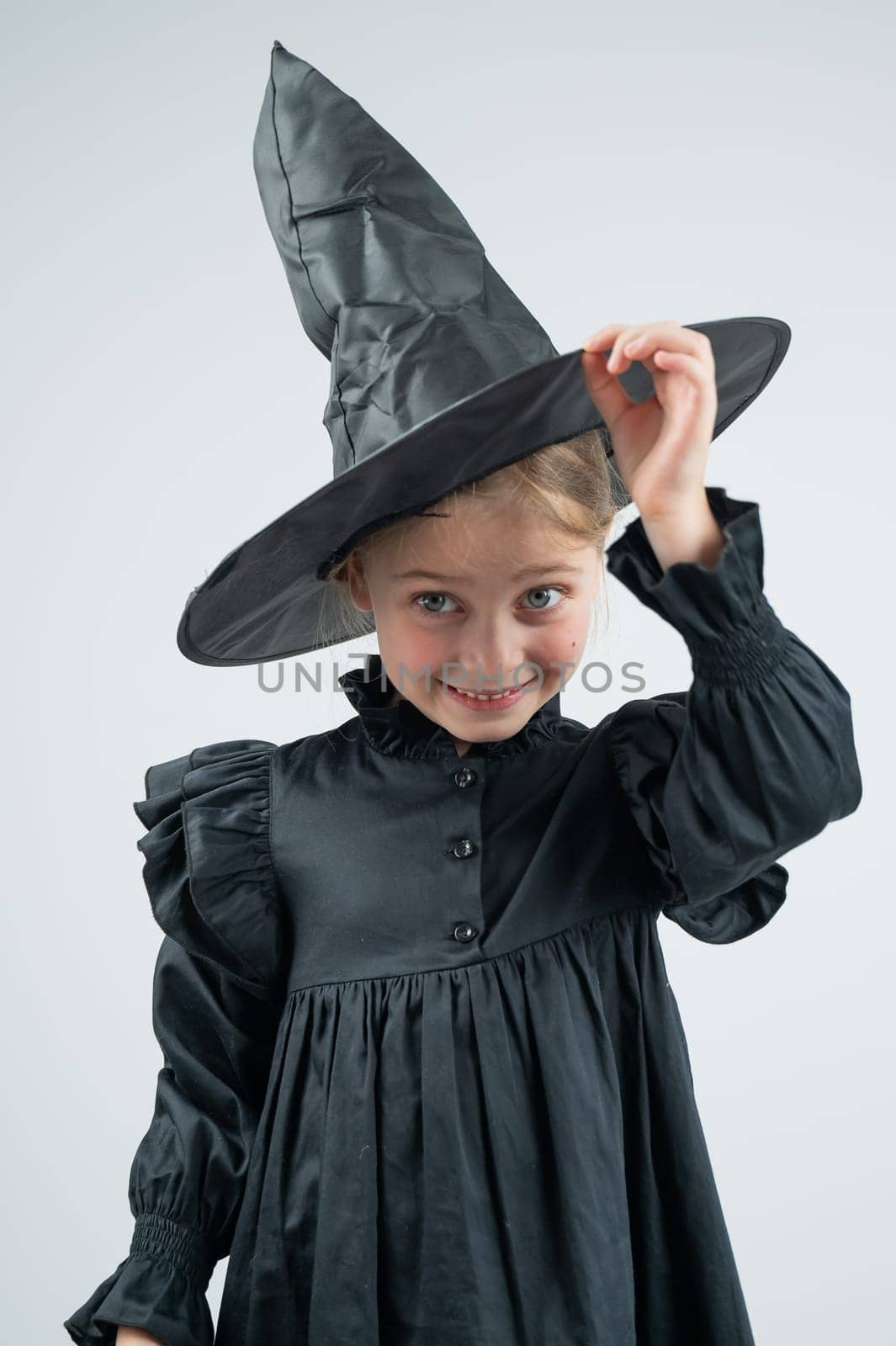 Portrait of a little Caucasian girl in a witch costume on a white background. Vertical photo. by mrwed54