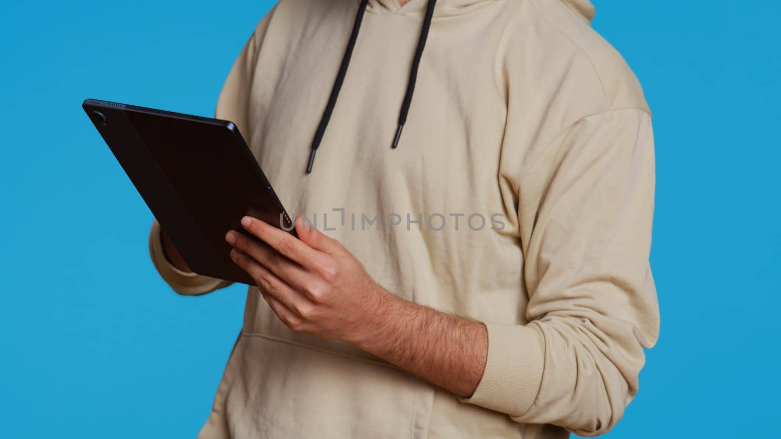 Arab guy using tablet to scroll on online websites, looking for something on the internet and using social media apps. Modern person working with touchscreen device in studio. Camera 2.