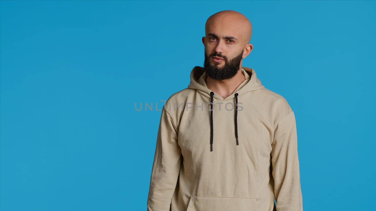 Young guy gesturing no sign over studio background, posing in studio and showing negative emotion. Middle eastern model doing forbidden gesture, expressing his refusal. Camera 1.