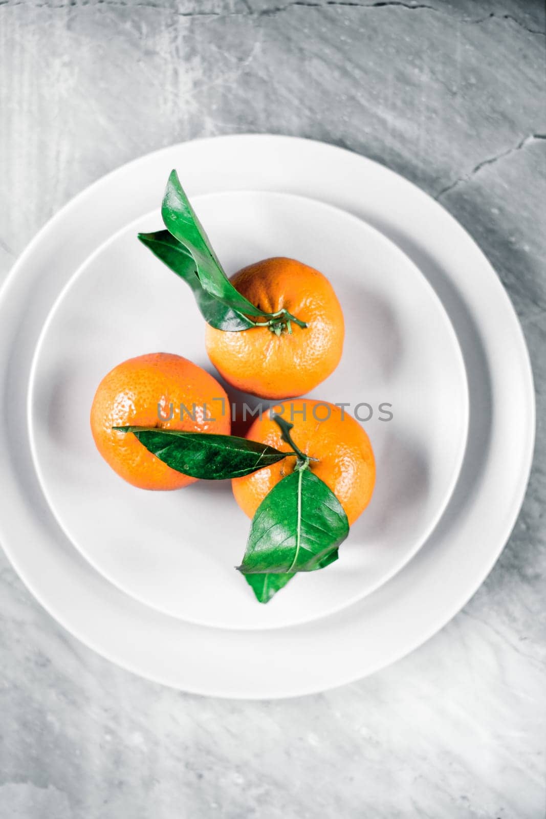 Tangerines with leaves on plate - citrus fruits and healthy eating flatlay styled concept