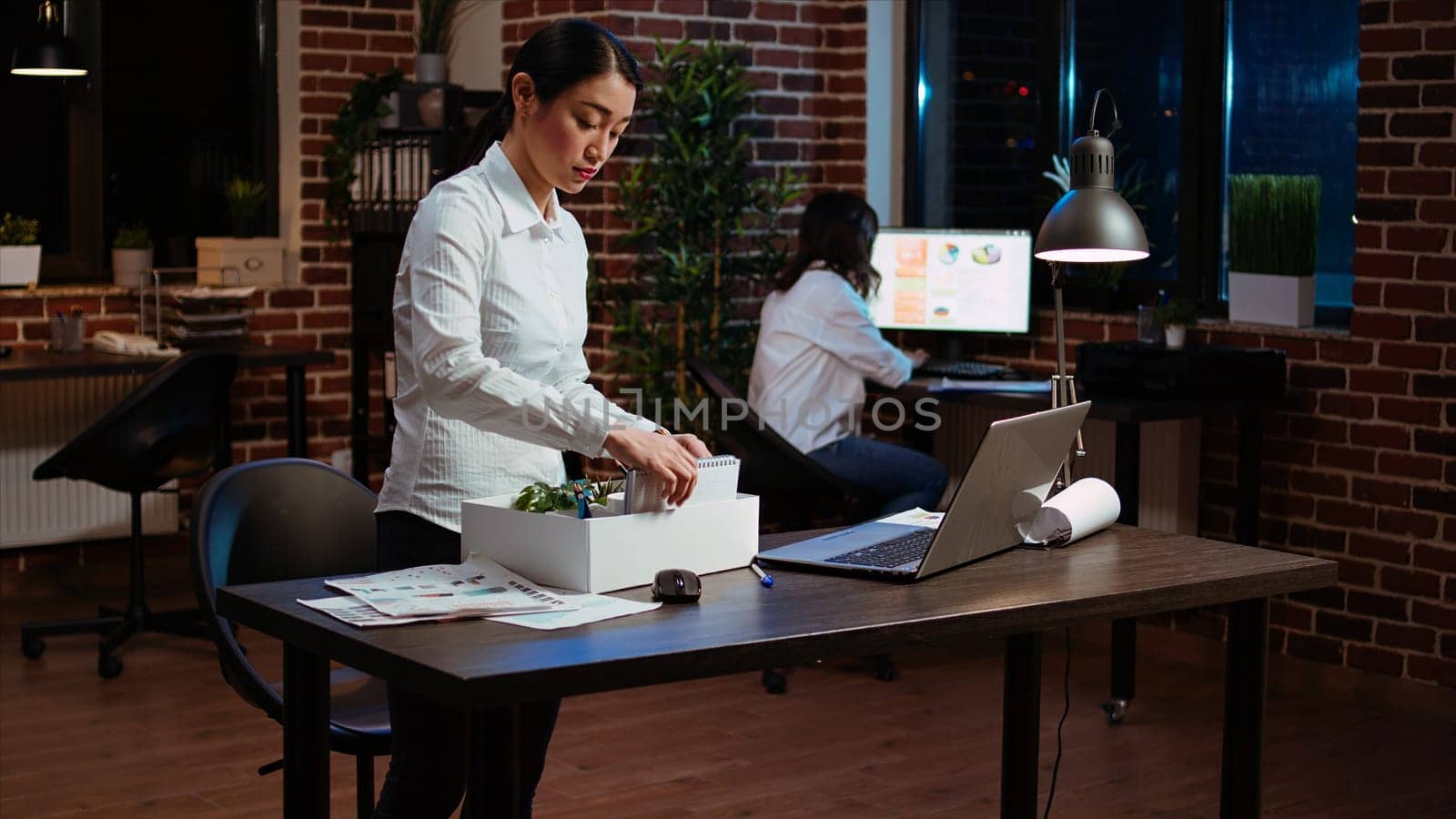 Sad employee packing desk things after quitting job, saying goodbye to colleague. Disappointed employee preparing to leave workplace after accepting another company position, camera A