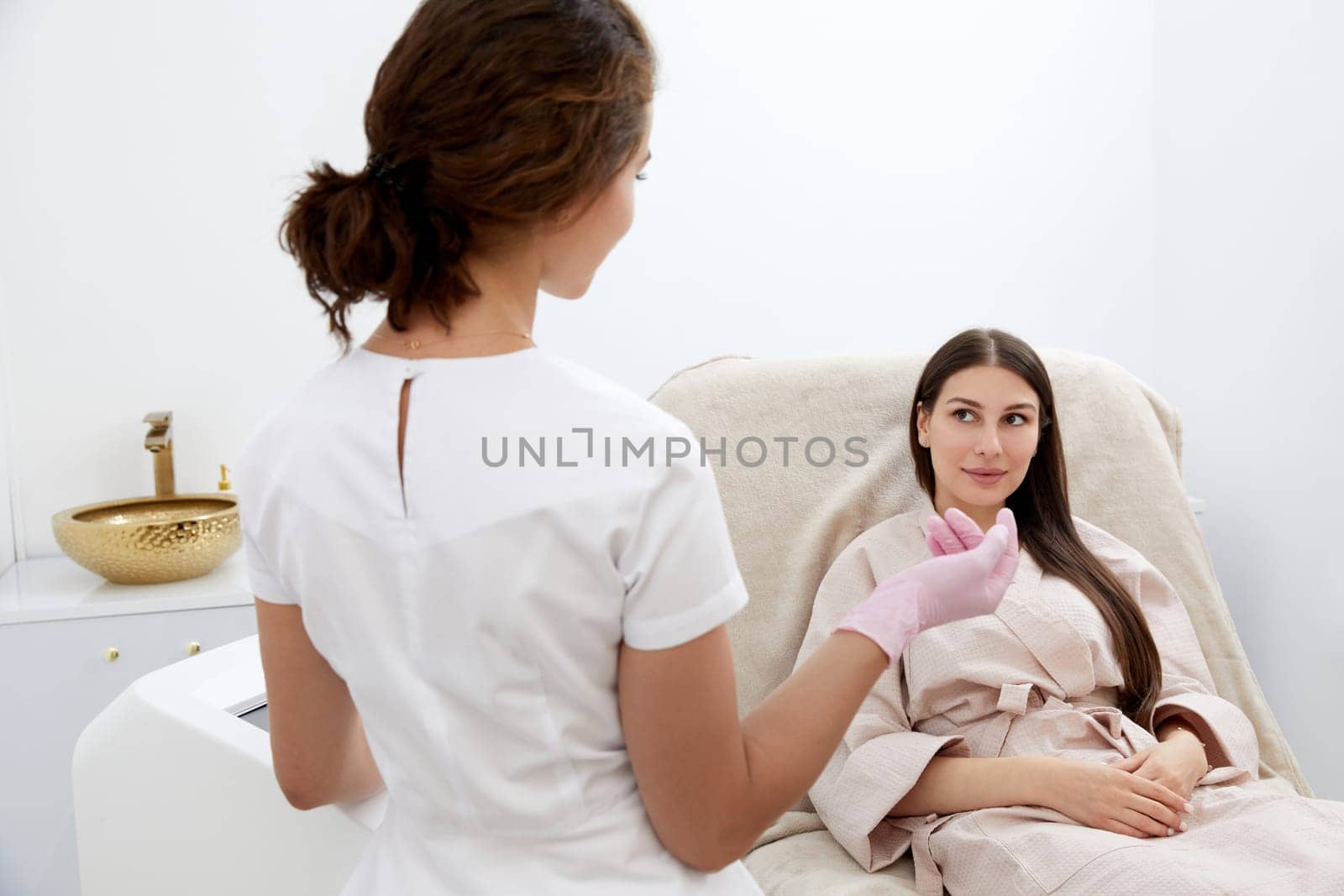 Within the clinic, a patient and young female cosmetologist have a deep discussion about available beauty procedures