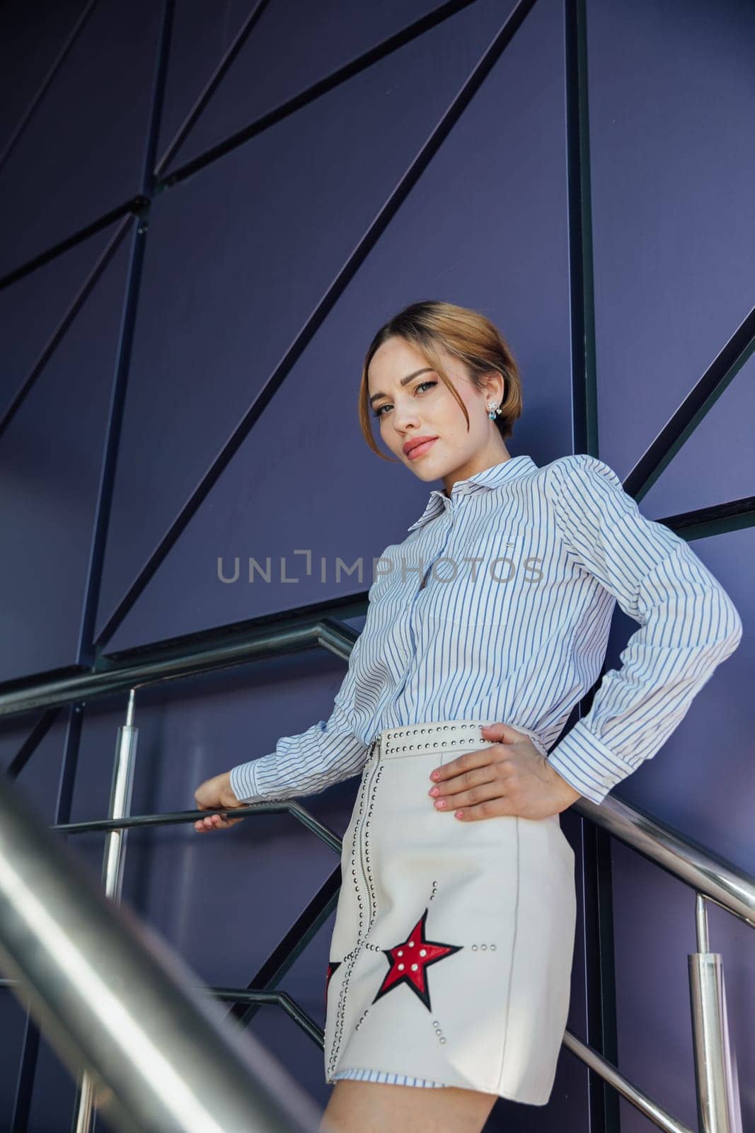 woman in fashionable clothes stands near the glass wall of the building walk on the street