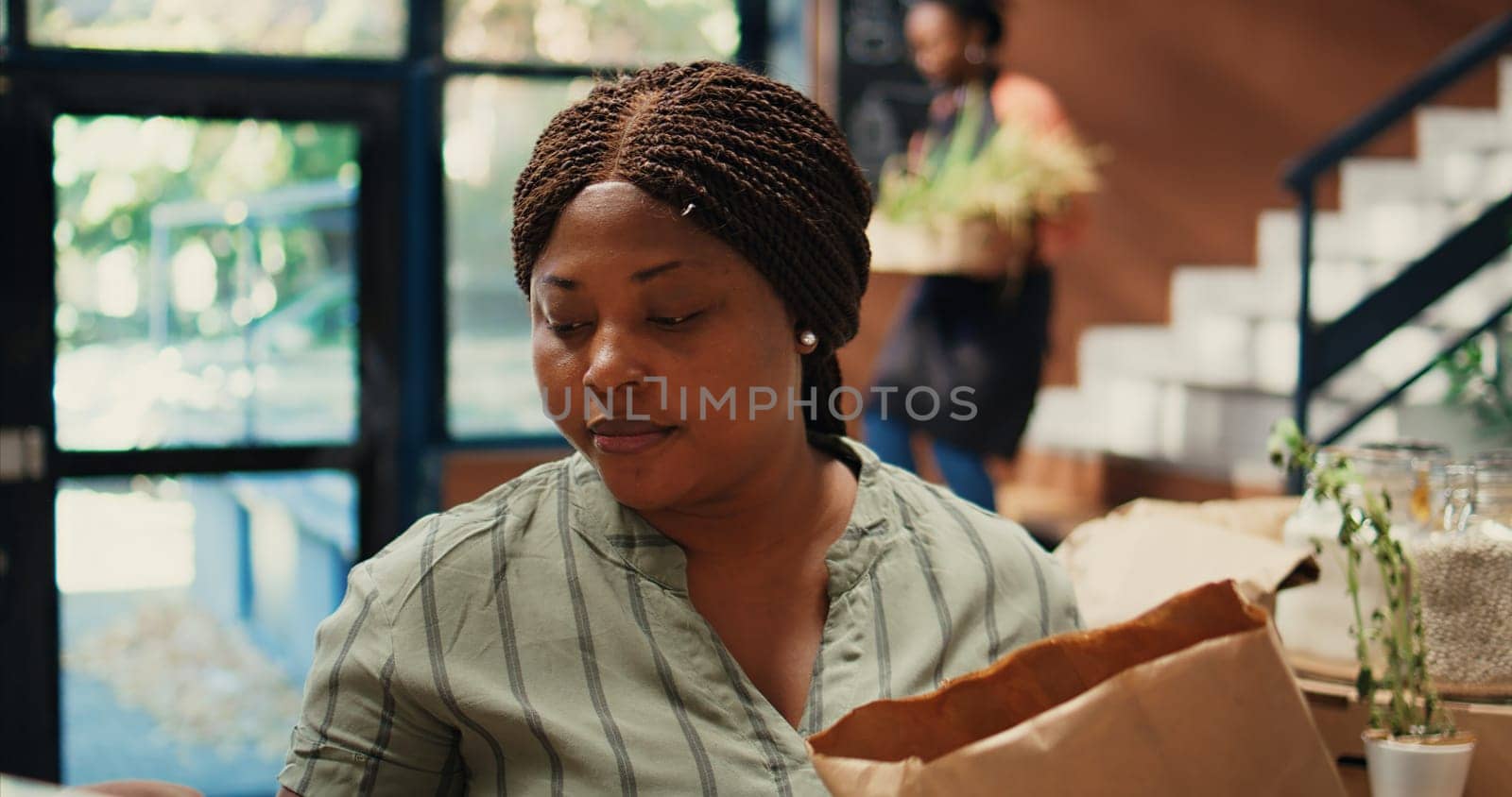 Buyer enjoying fresh smell of locally grown lemons from farm, smelling citric aroma and putting ecological fruits in a bag. African american client looking for homegrown goods. Tripod shot.