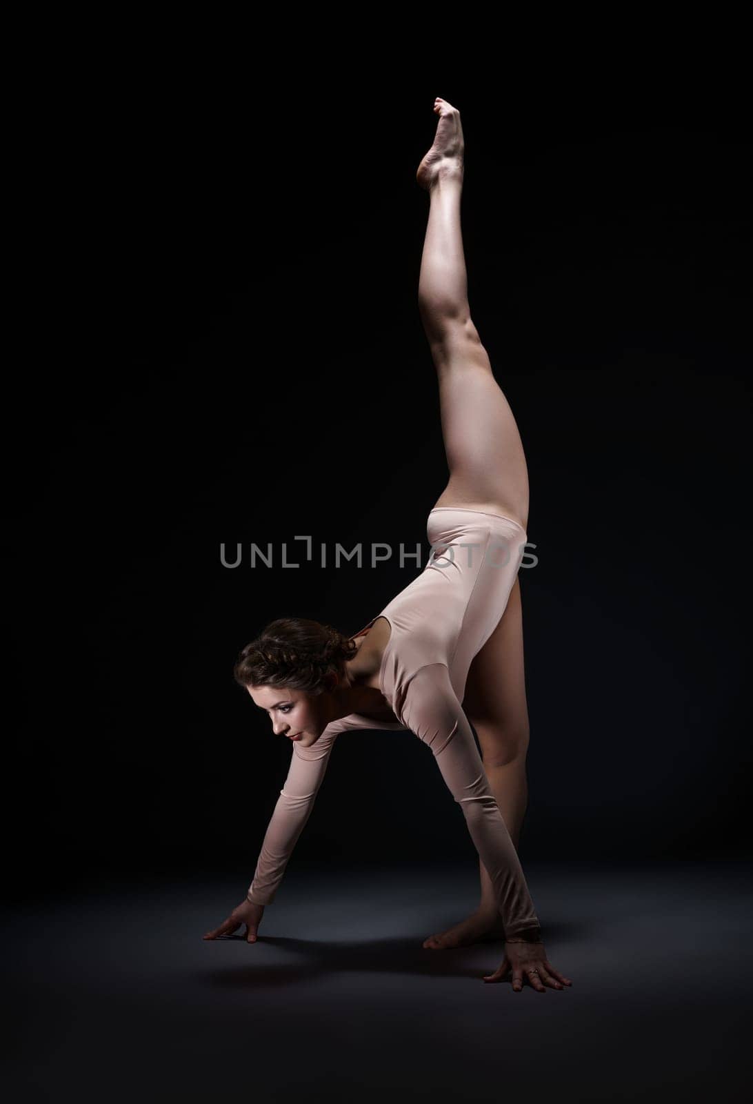 Studio photo of artistic gymnast posing while doing split