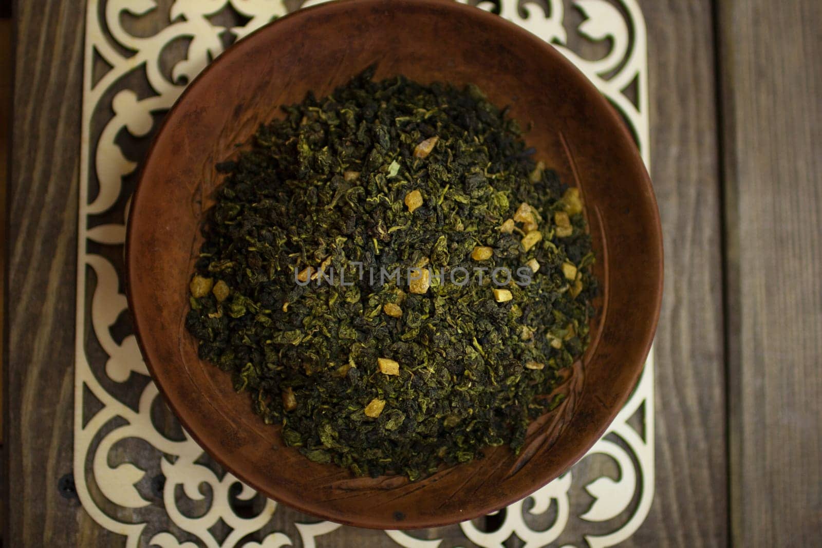 A clay plate with green fruit tea stands on a wooden table. by VeronikaAngo