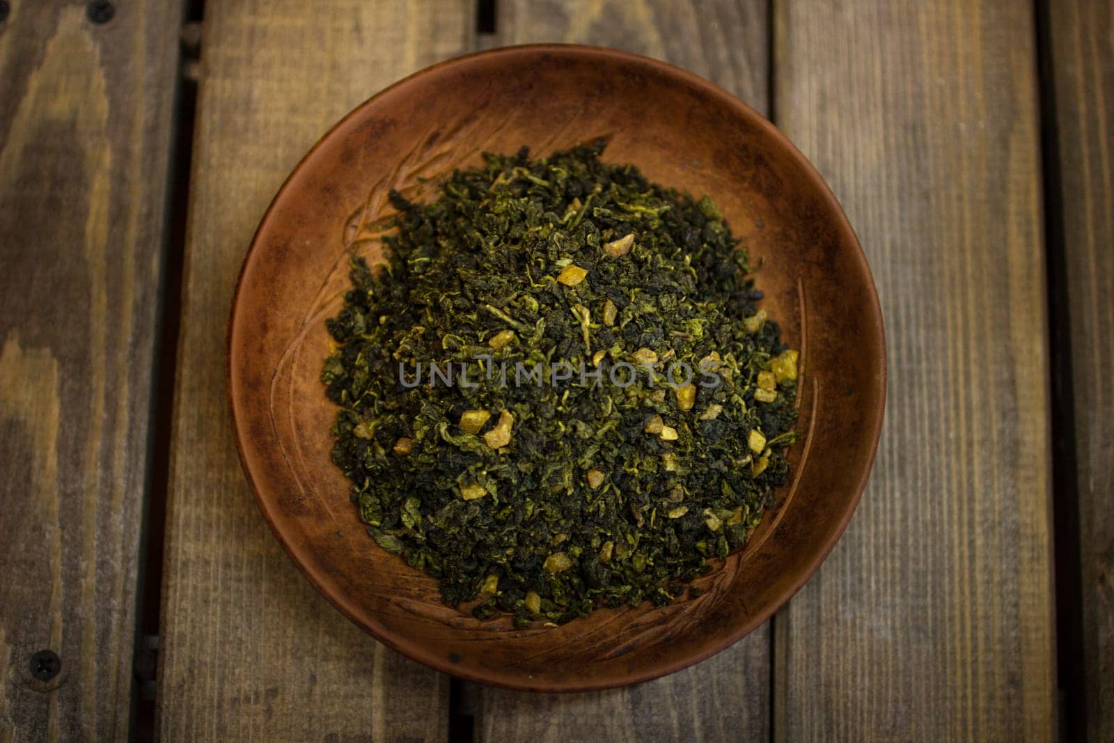 A clay plate with green fruit tea stands on a wooden table. by VeronikaAngo