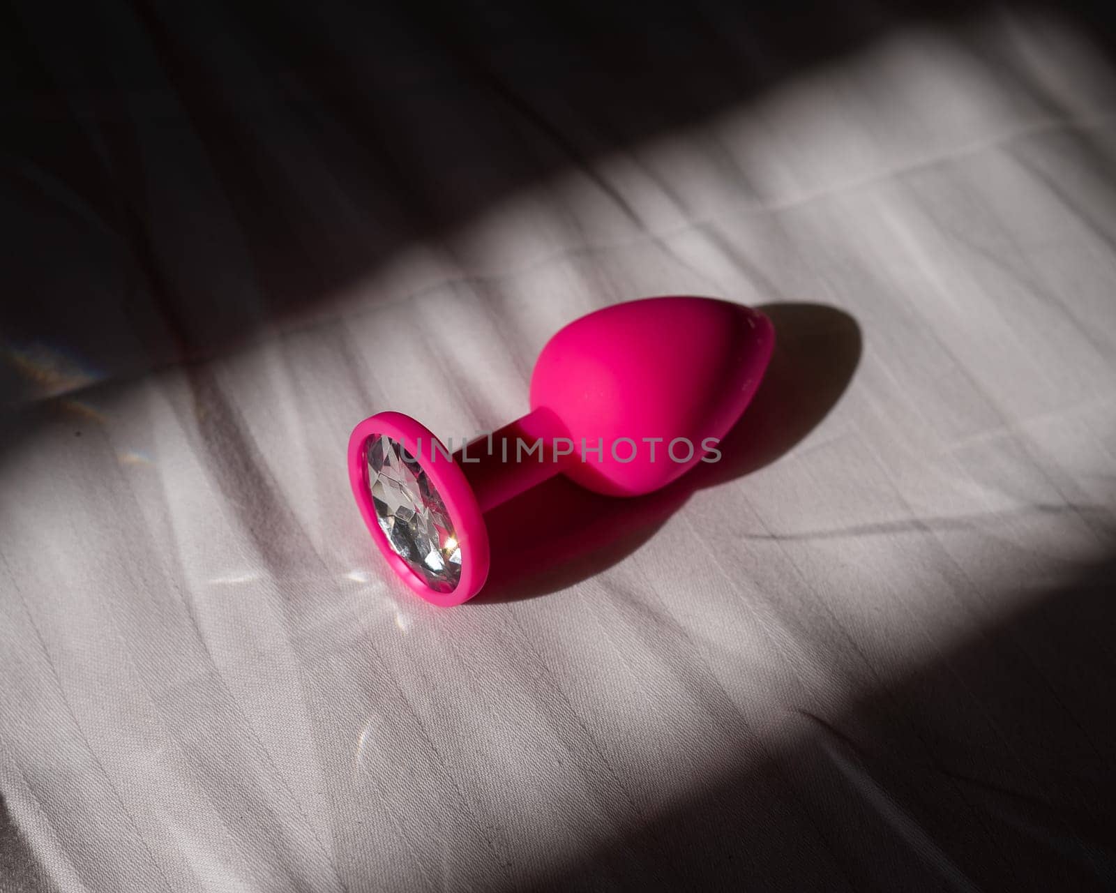 Pink silicone anal plug on a white sheet