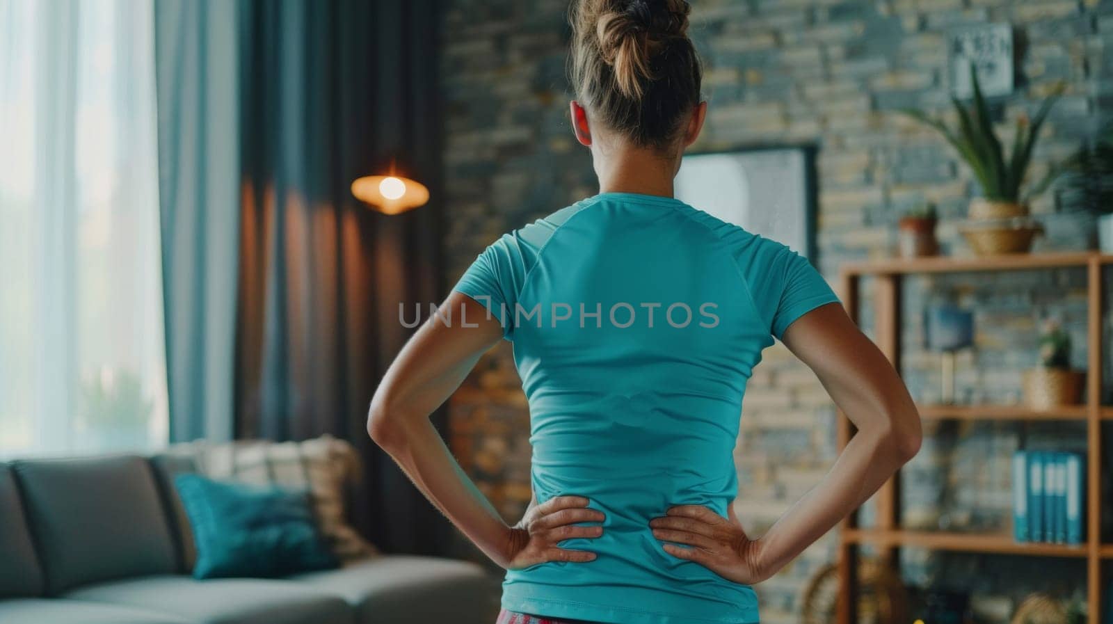 Back of a woman with hand on her back showing back pain at home.