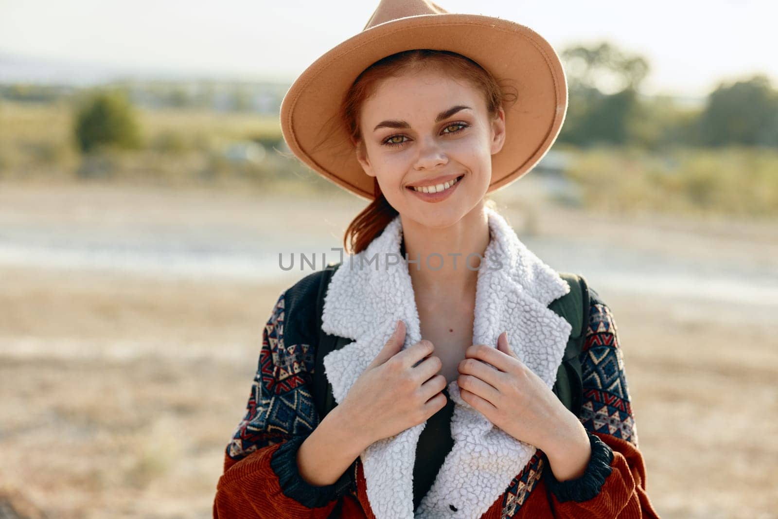 Woman in stylish hat and sweater posing gracefully in lush field on a sunny day