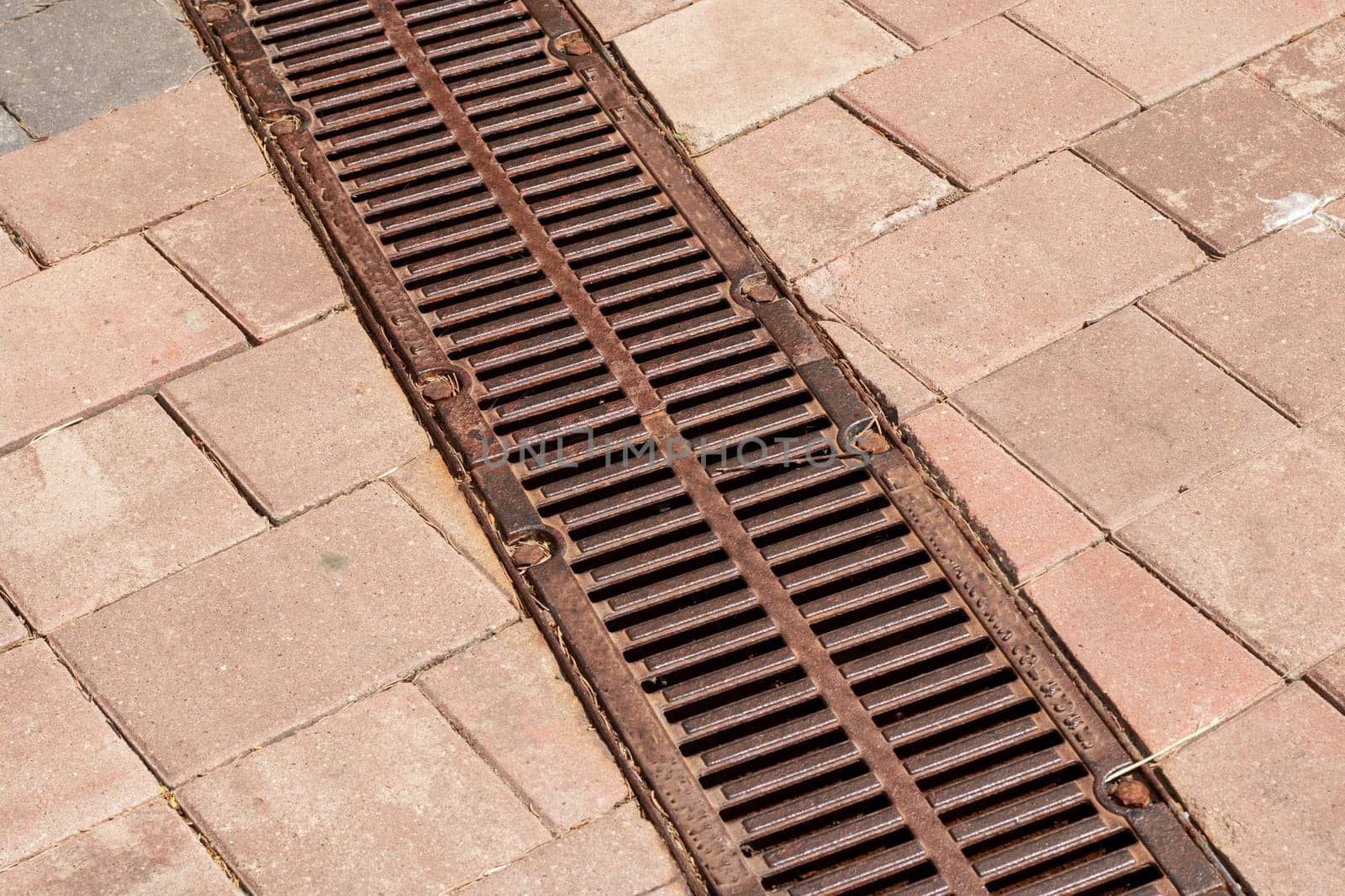 A closeup view of a drain located on a brick sidewalk, showcasing the intricate details and texture of the surface