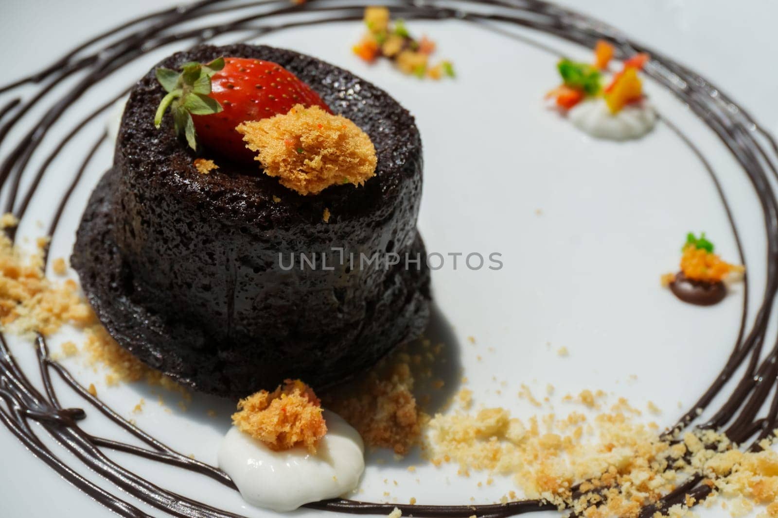 Delicious chocolate fondant or lava cake with cream, strawberry, and cake biscuit crumbles, Hot chocolate dessert pudding with liquid chocolate center, fondant au chocolate for cooking ideas and recipe