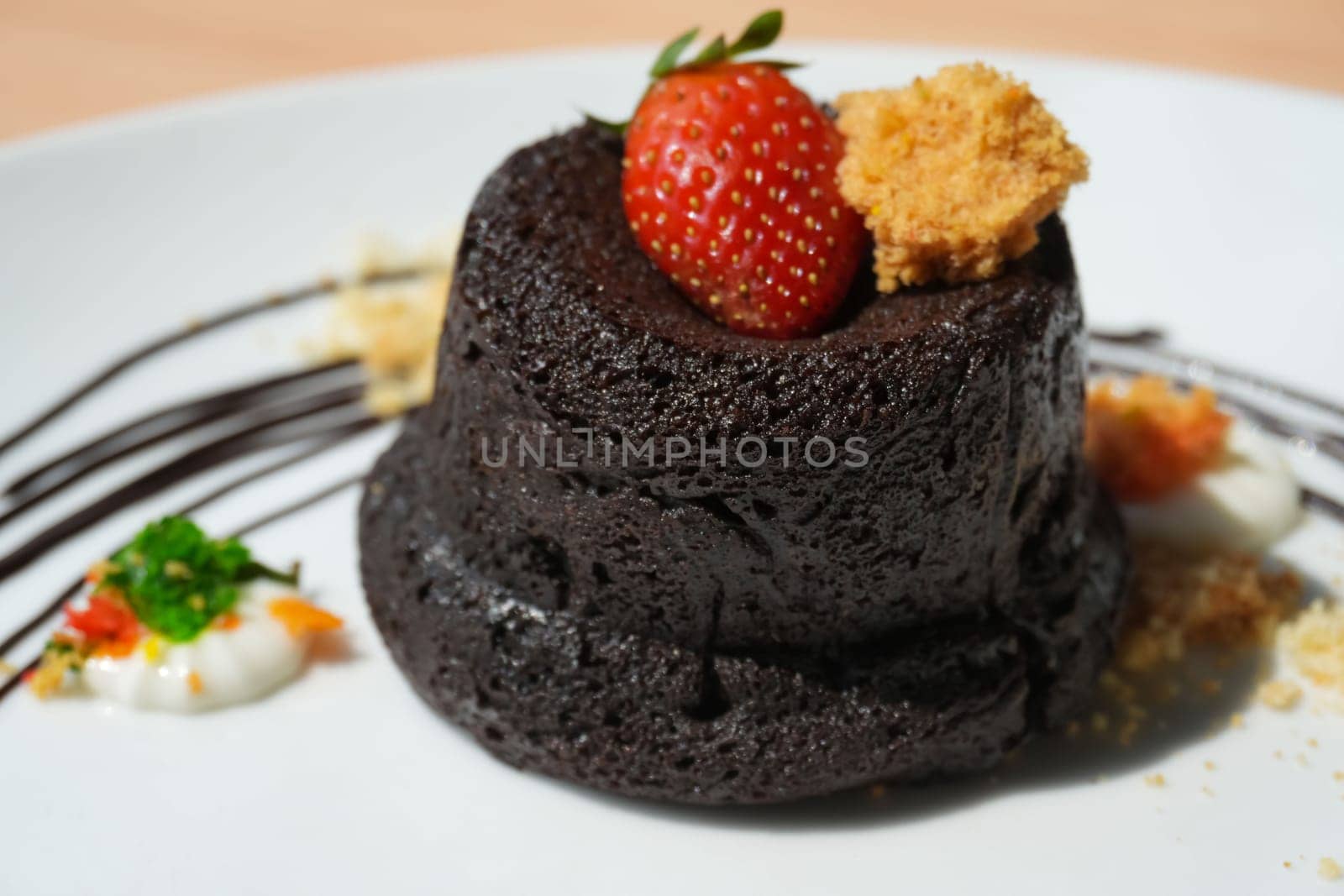 Delicious chocolate fondant or lava cake with cream, strawberry, and cake biscuit crumbles, Hot chocolate dessert pudding with liquid chocolate center, fondant au chocolate for cooking ideas and recipe