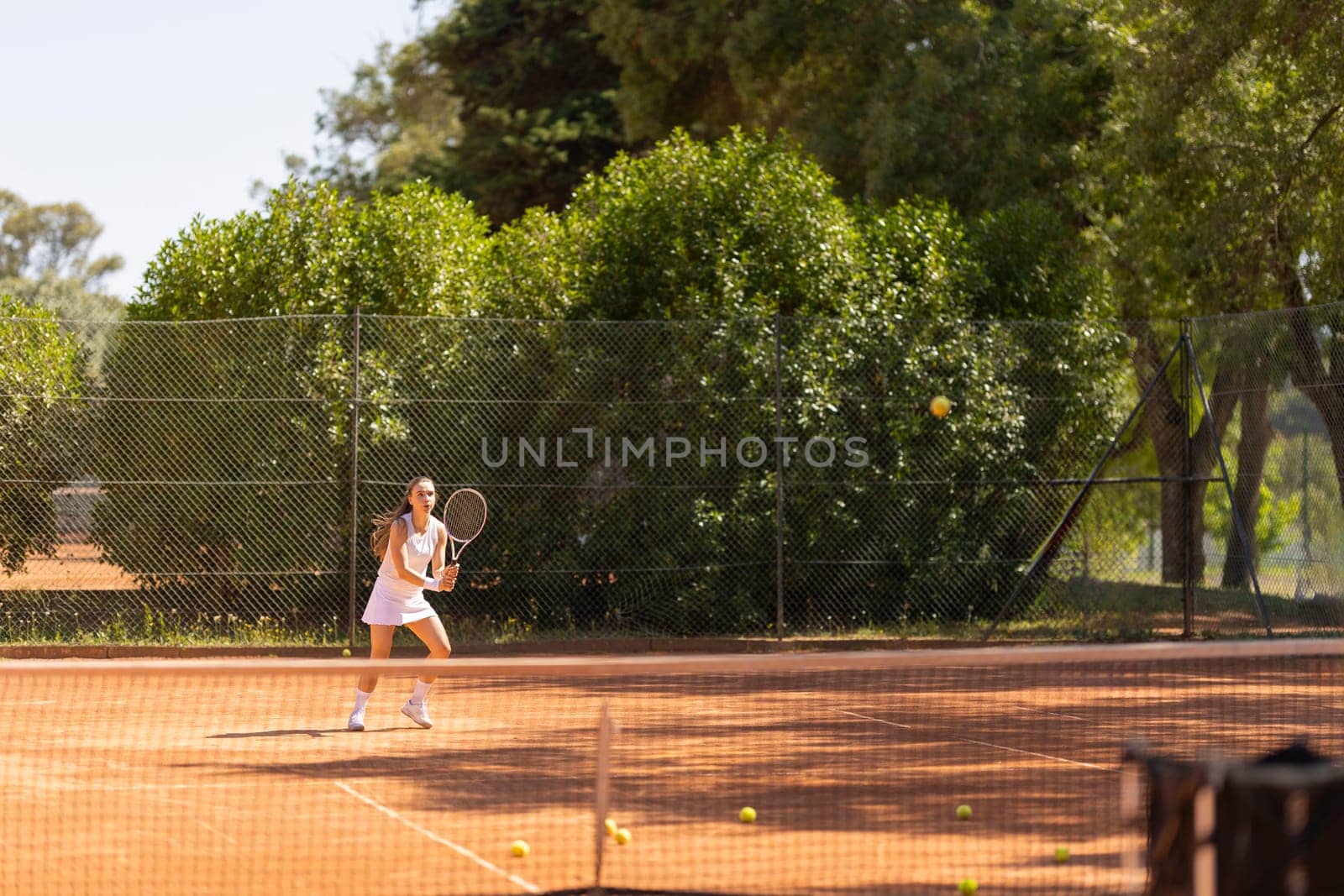 A woman is playing tennis on a court with a net. She is holding a tennis racket and is about to hit a tennis ball