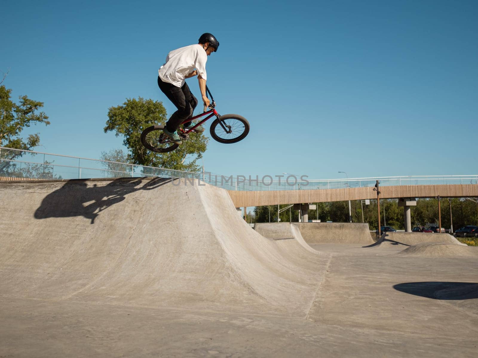 Skilled BMX rider performing aerial trick in quarter pipe in ramp park. Young BMX bicycle rider having fun and posing in jumping outdoors. Concrete quarter street park and BMX rider in air stunt.