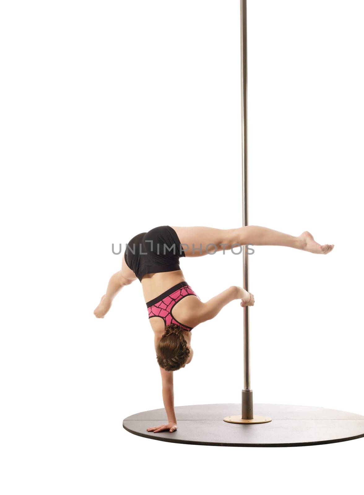 Studio photo of flexible female athlete training on pylon