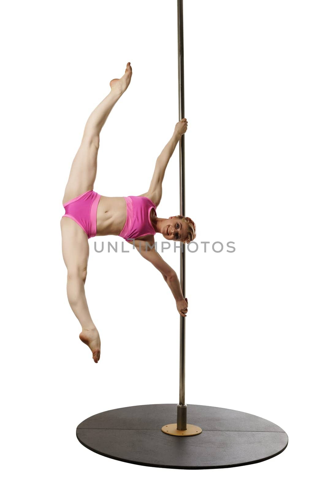 Smiling female gymnast poses during workout on pole