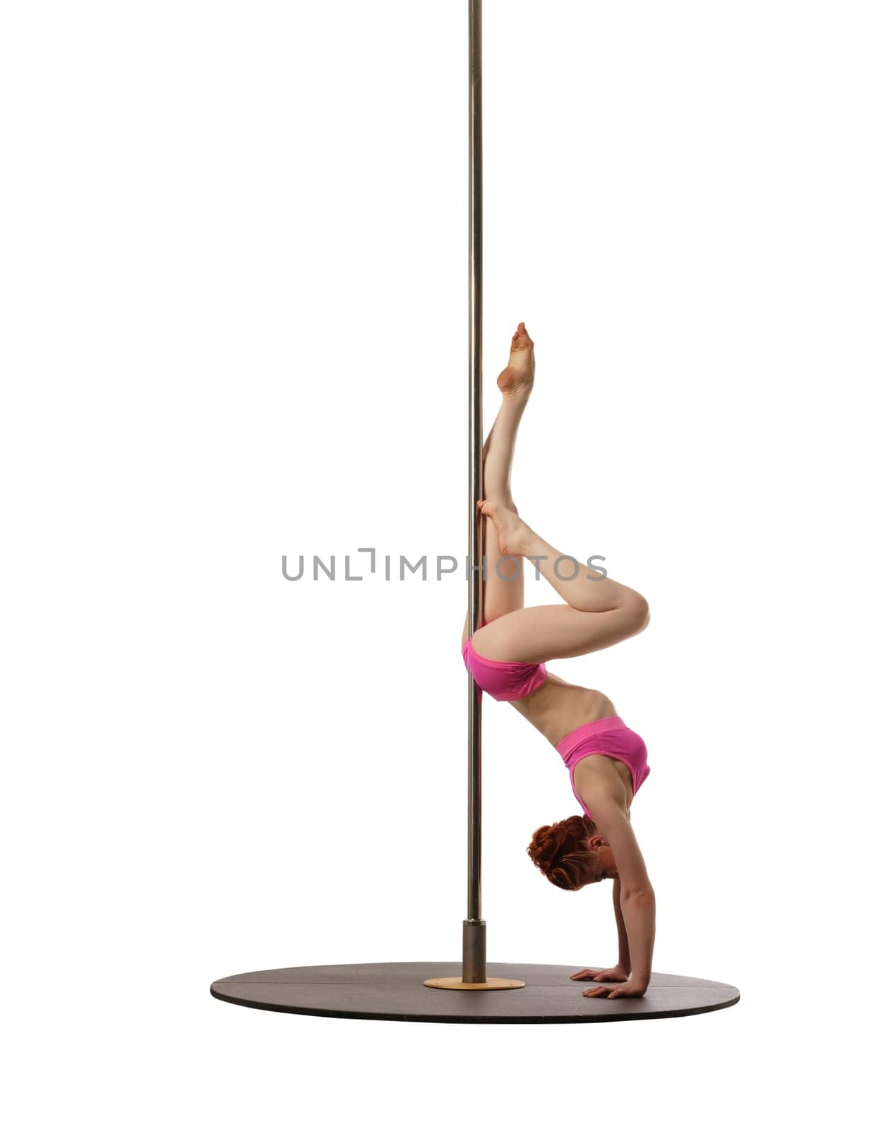 Pole dance. Red-haired woman doing handstand, isolated on white