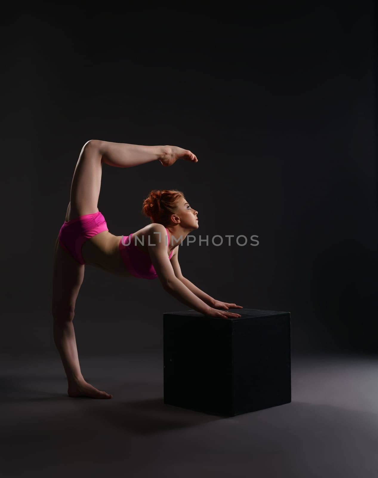 Flexible ballet dancer training on cube in studio