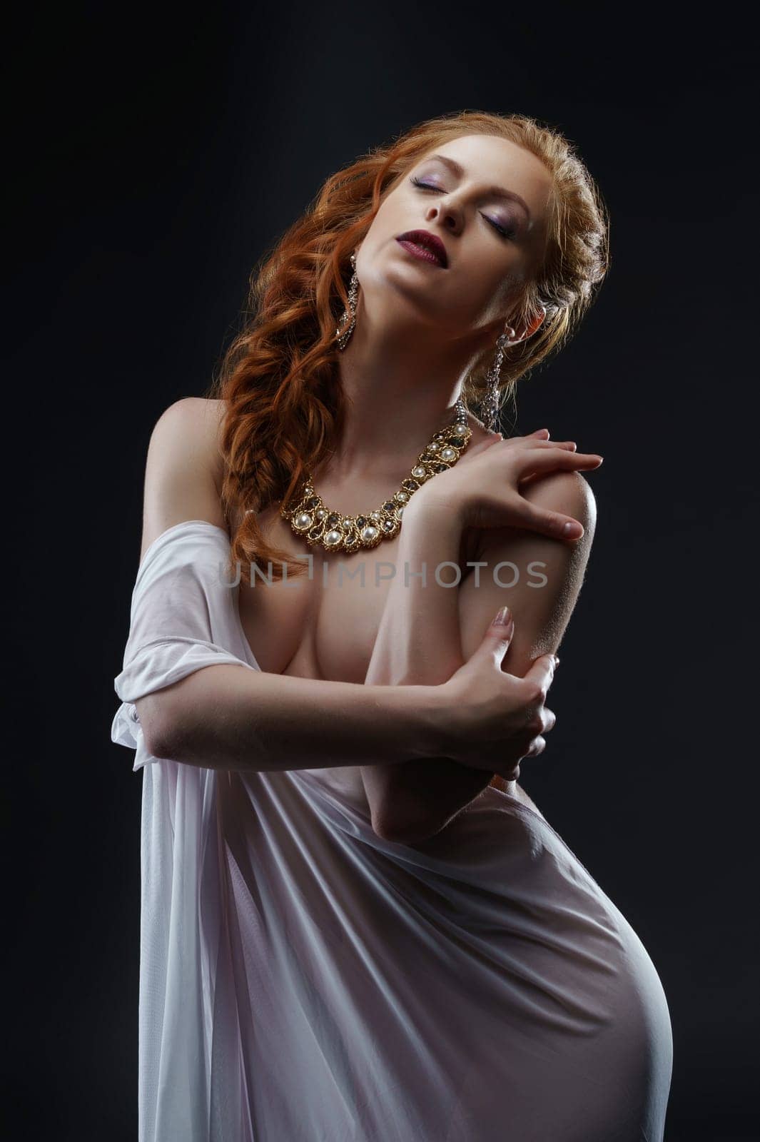 Sensuality and luxury. Red-haired model posing at camera
