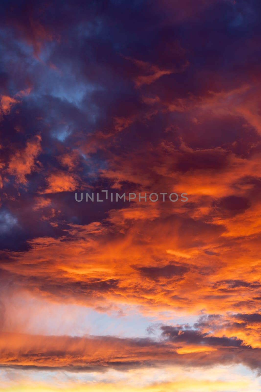 Dramatic fiery sky with dark red fluffy clouds, evening or morning dusk and golden sunlight