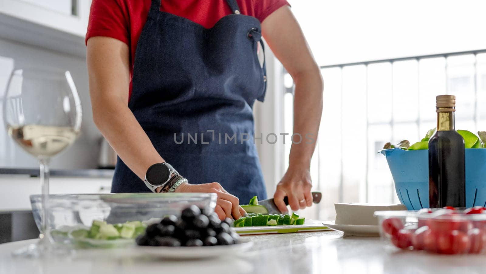 Woman'S Hands Are Slicing Cucumber For Greek Salad With A Glass Of White Wine Nearby