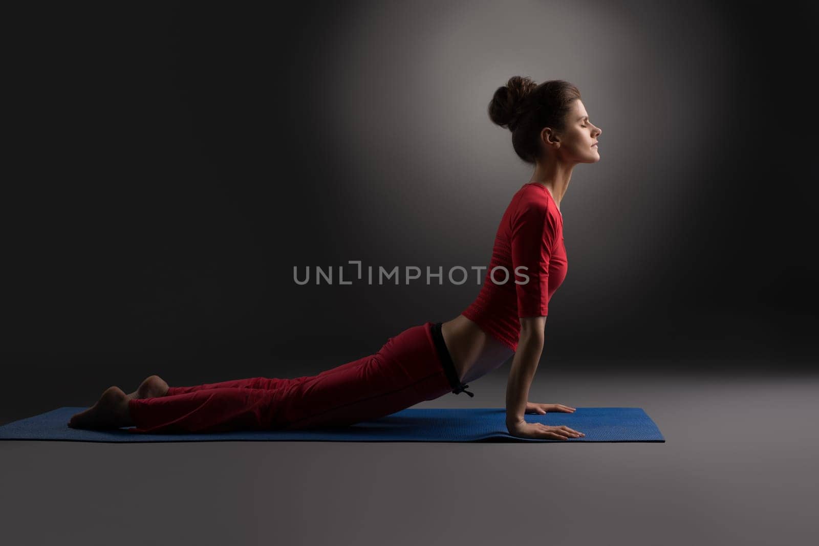 Pilates. Beautiful woman exercising in studio, on gray background