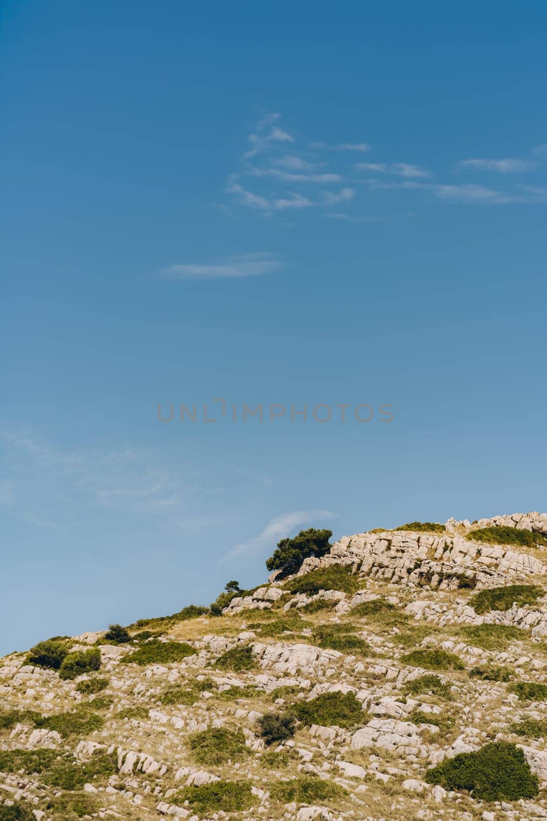 Rocky hill and clouds in blue sky, Dugi Otok island in Croatia by Popov