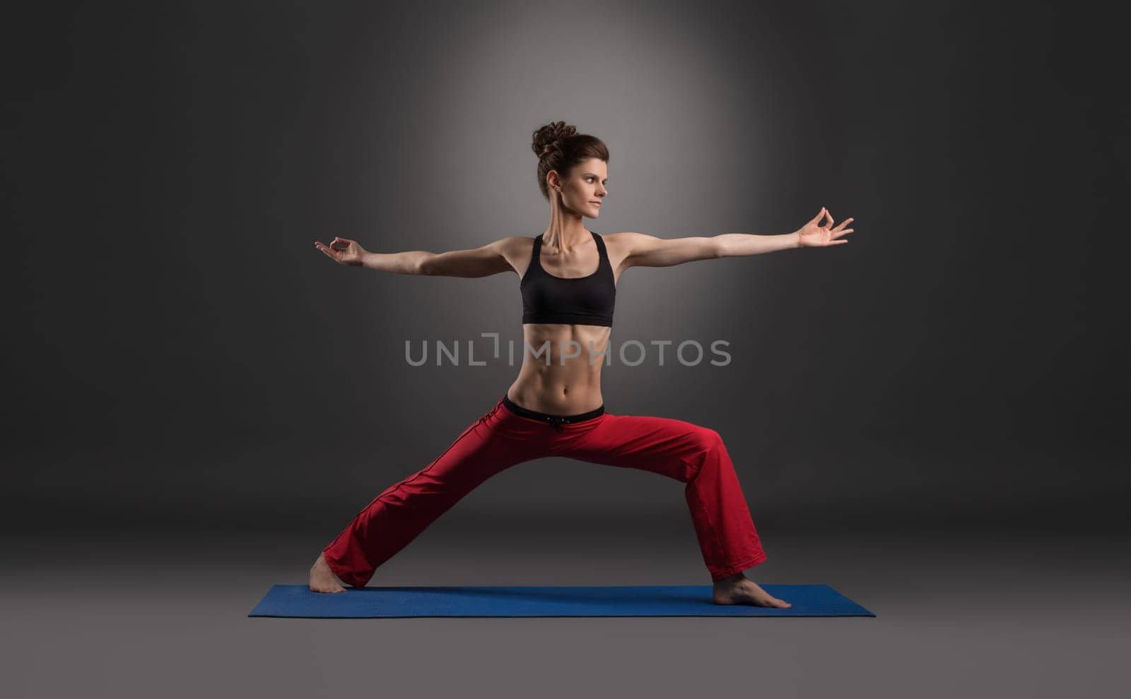 Woman practicing yoga in studio, on gray background