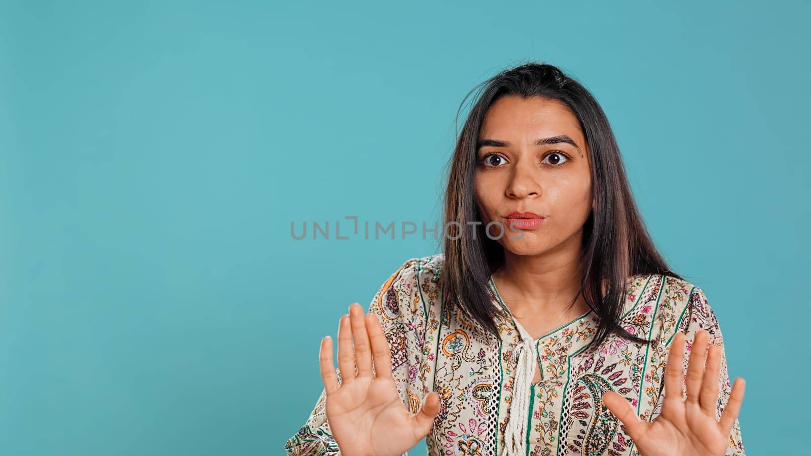 Stern indian woman doing stop hand gesture sign, complaining. Authoritative person doing firm halt sign gesturing, wishing to end concept, isolated over studio background, camera B