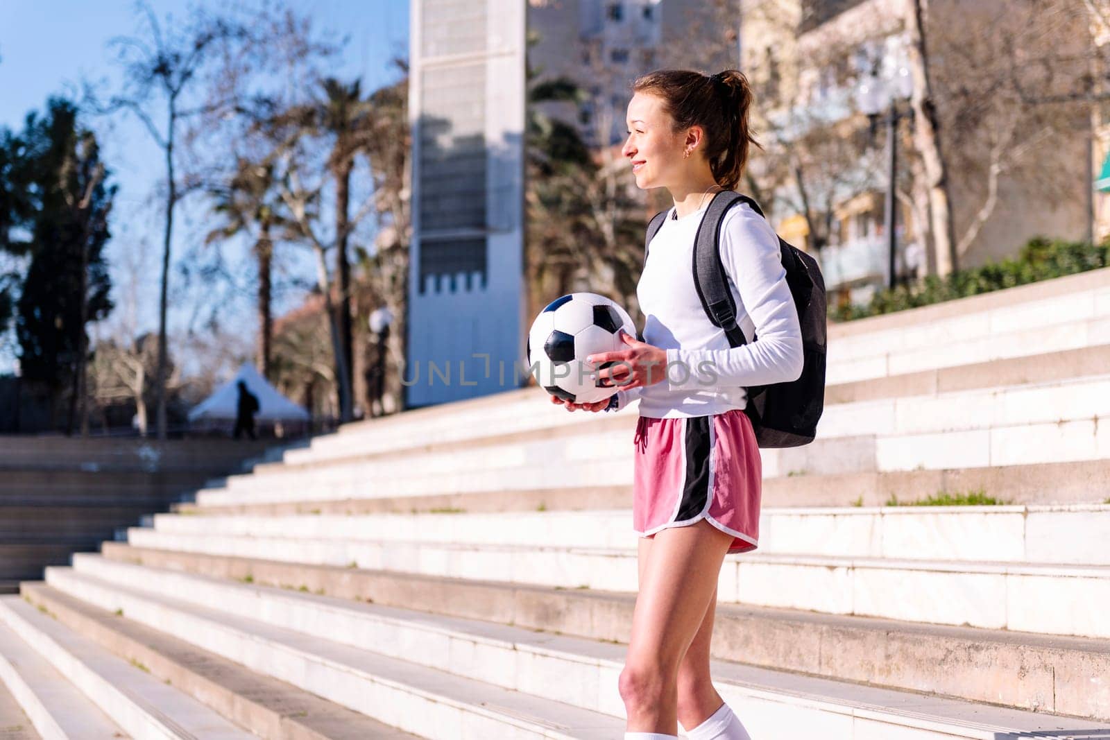 smiling caucasian woman walking at park with a soccer ball in hand, concept of sport and active lifestyle