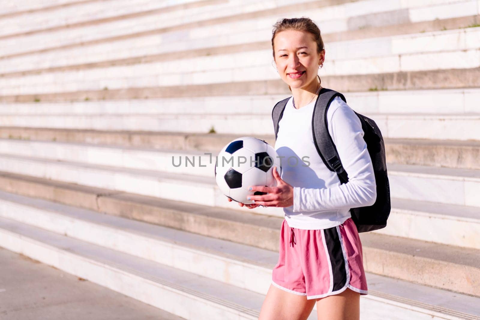 smiling caucasian woman looking at camera with a soccer ball in hand, concept of sport and active lifestyle, copy space for text